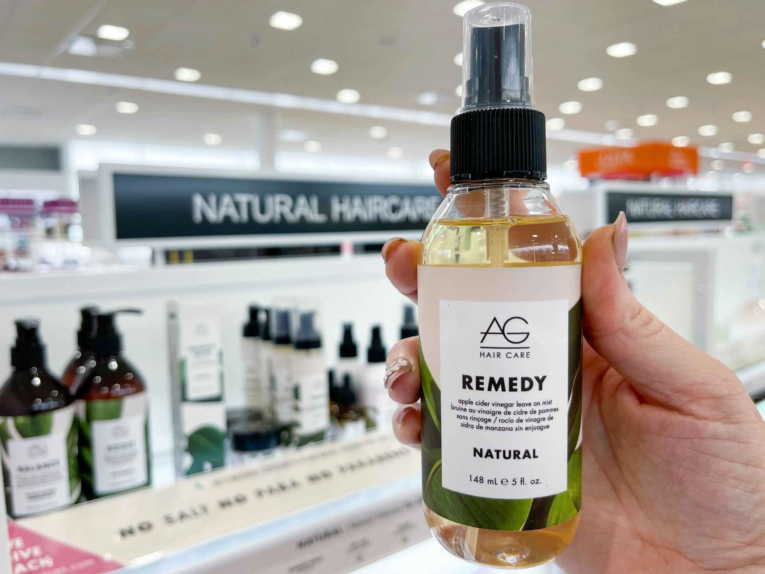 Woman holding hair product in front of display
