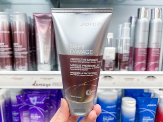 Woman holding bottle of Joico protective hair mask.