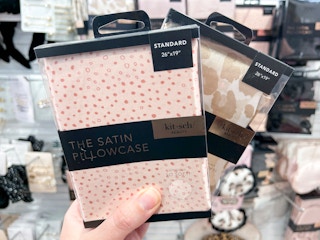 Woman holding two packs of satin pillowcases.