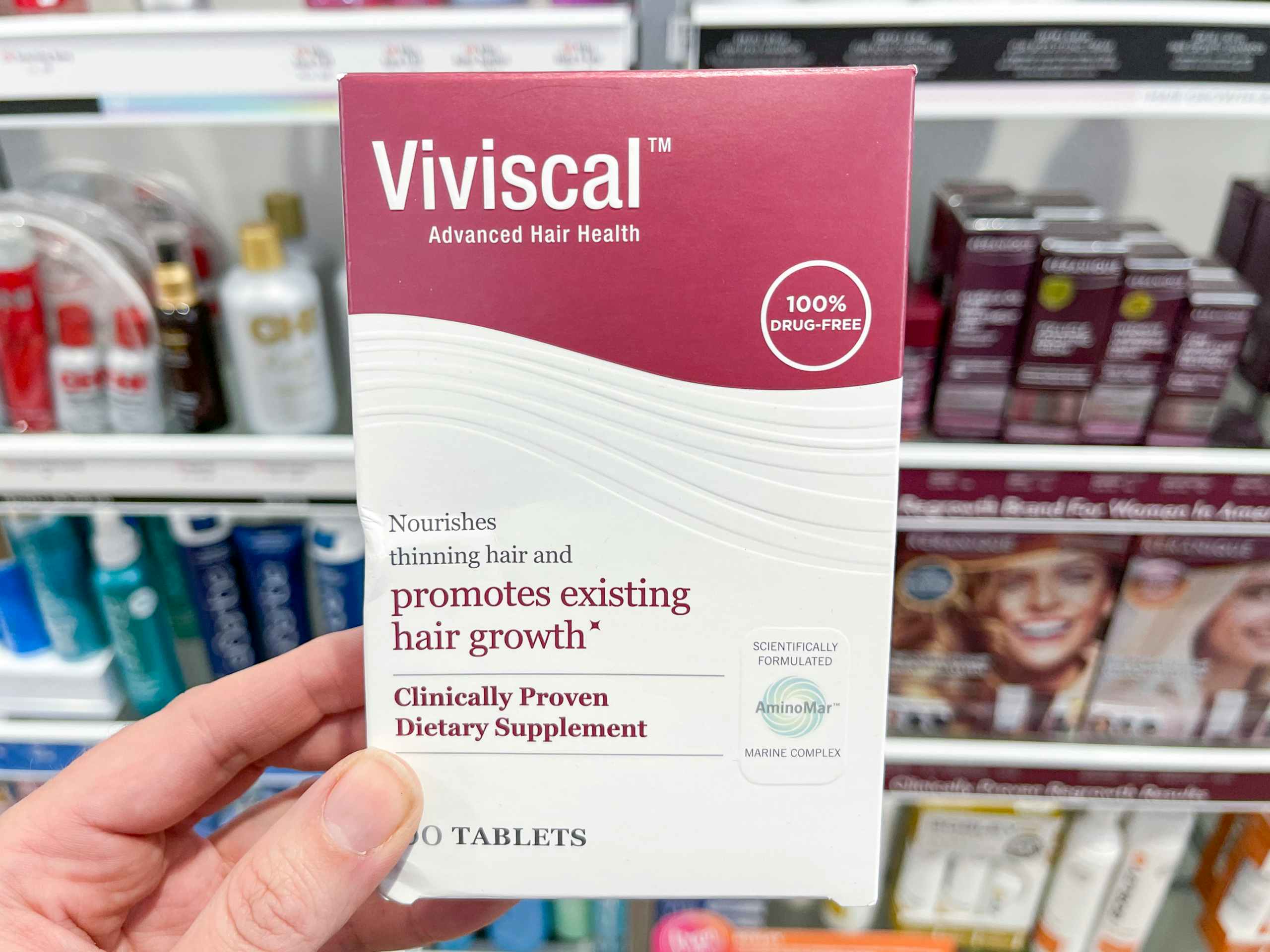 Woman holding box of Viviscal hair growth supplements.