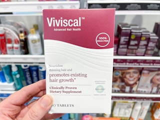 Woman holding box of Viviscal hair growth supplements.