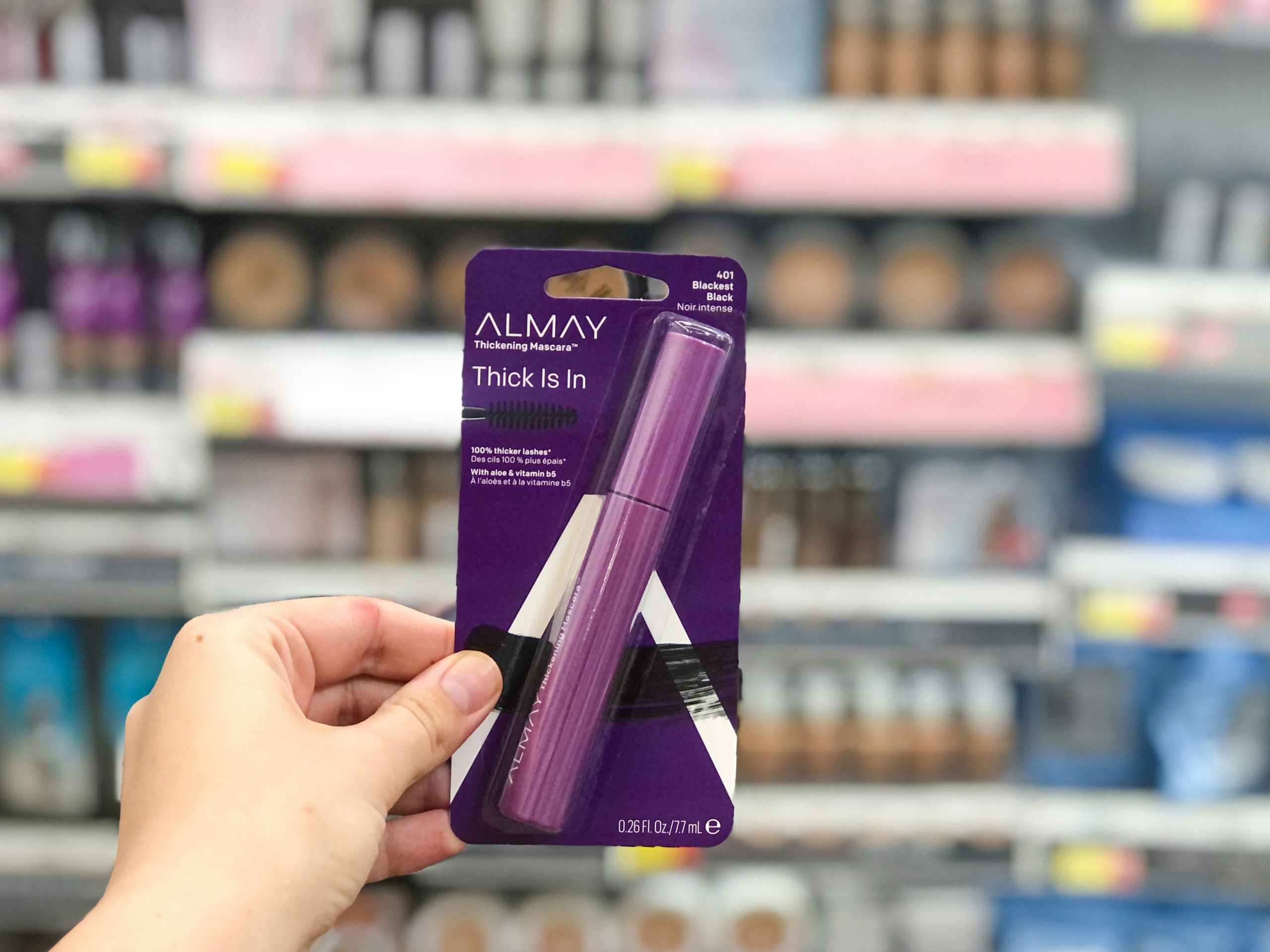 holding almay mascara package in front of makeup shelf