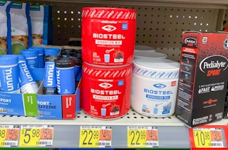 two bright red cans of biosteel hudration mix stacked one on top of the other on walmart shelf showing price tag