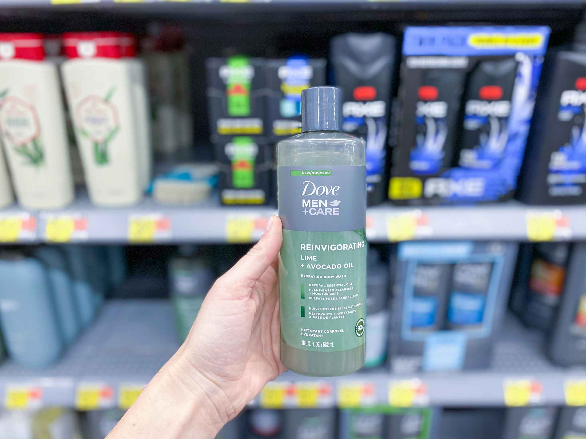 woman's left hand holding a bottle of dove men+care naturals body wash in front of men's body wash shelves at walmart