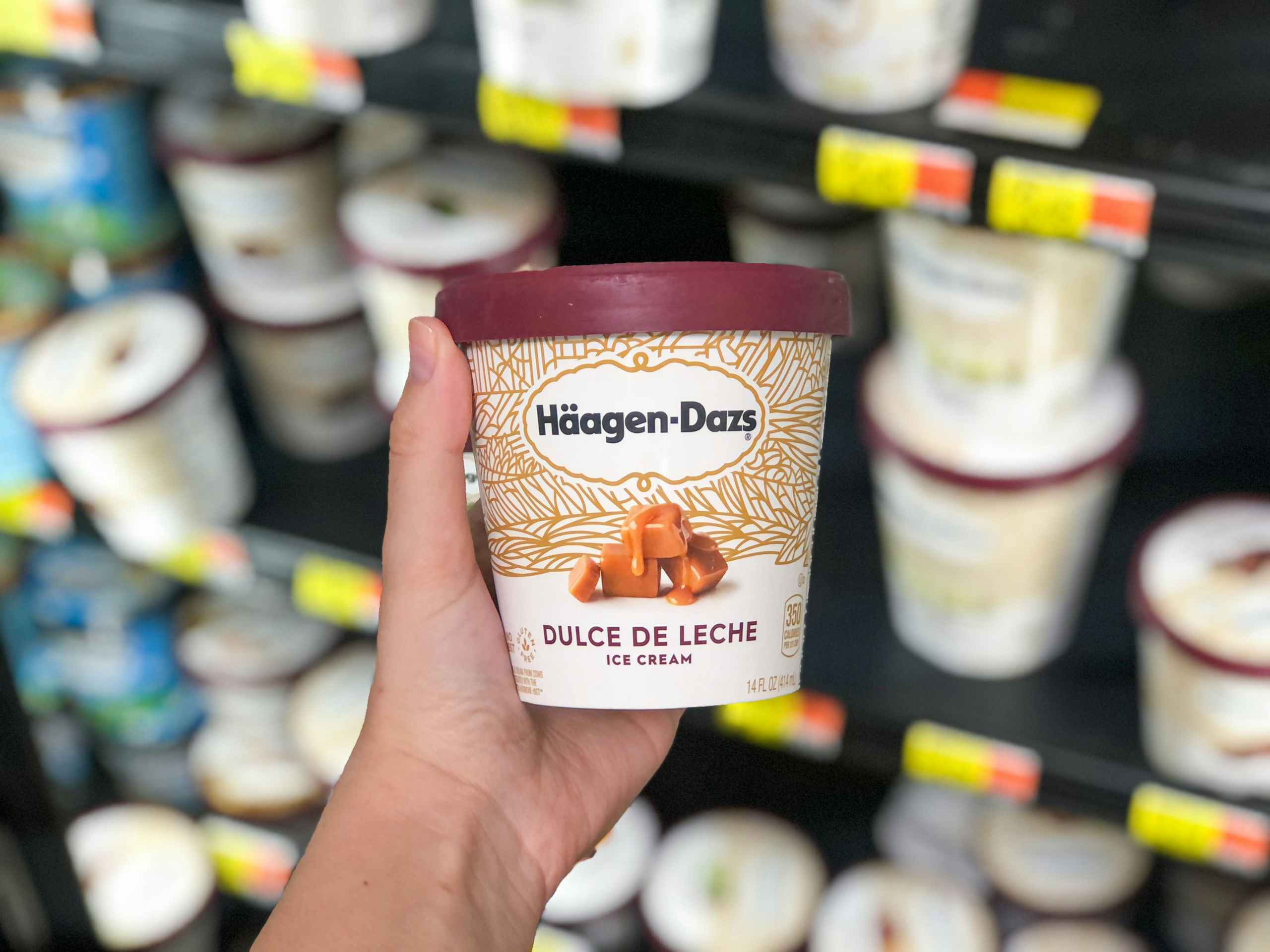 holding ice cream in front of ice cream shelf