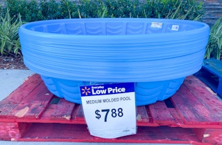 A stack of plastic kiddie pools sitting on a pallet at Walmart, marked as $7.88