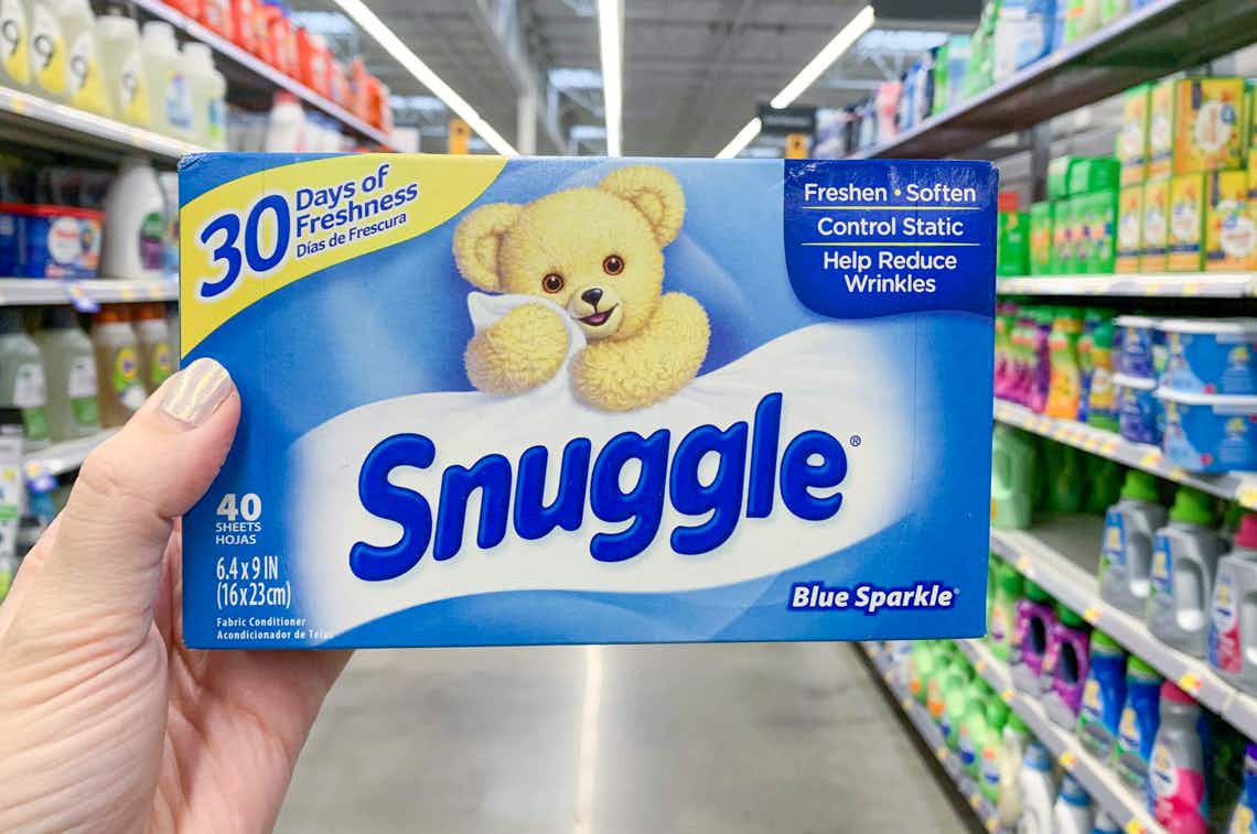 left hand holding box of snuggle dryer sheets in center of laundry aisle at walmart