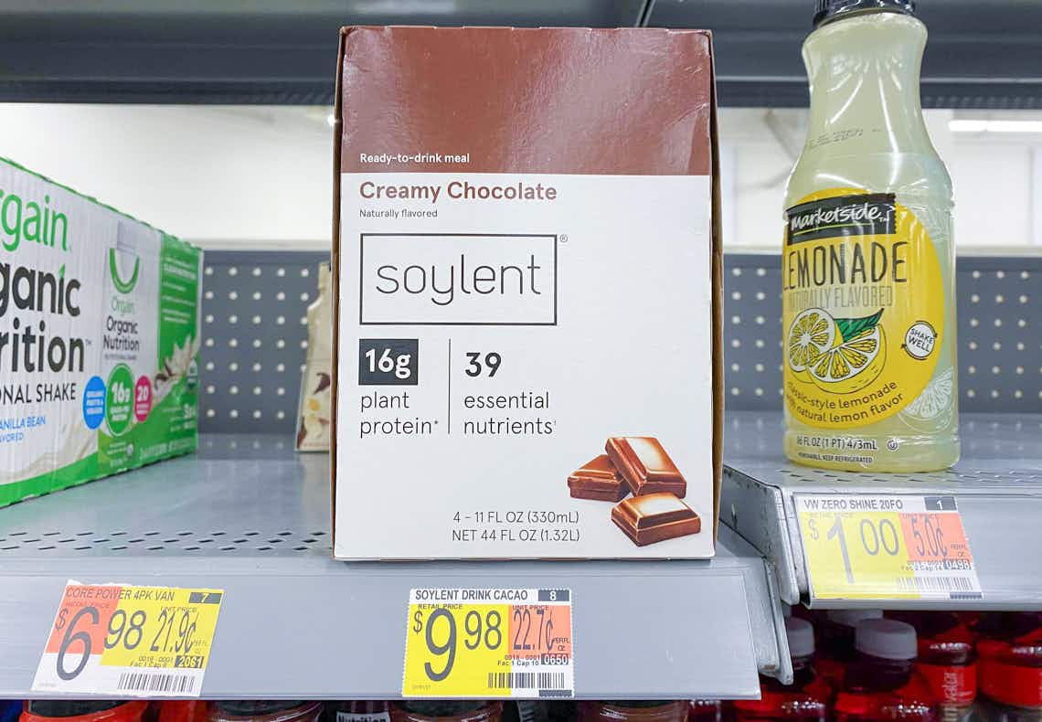 mostly empty walmart shelf with a misplaced bottle of lemonade and a box of soylent meal replacement drink taking the focus above the product price tag