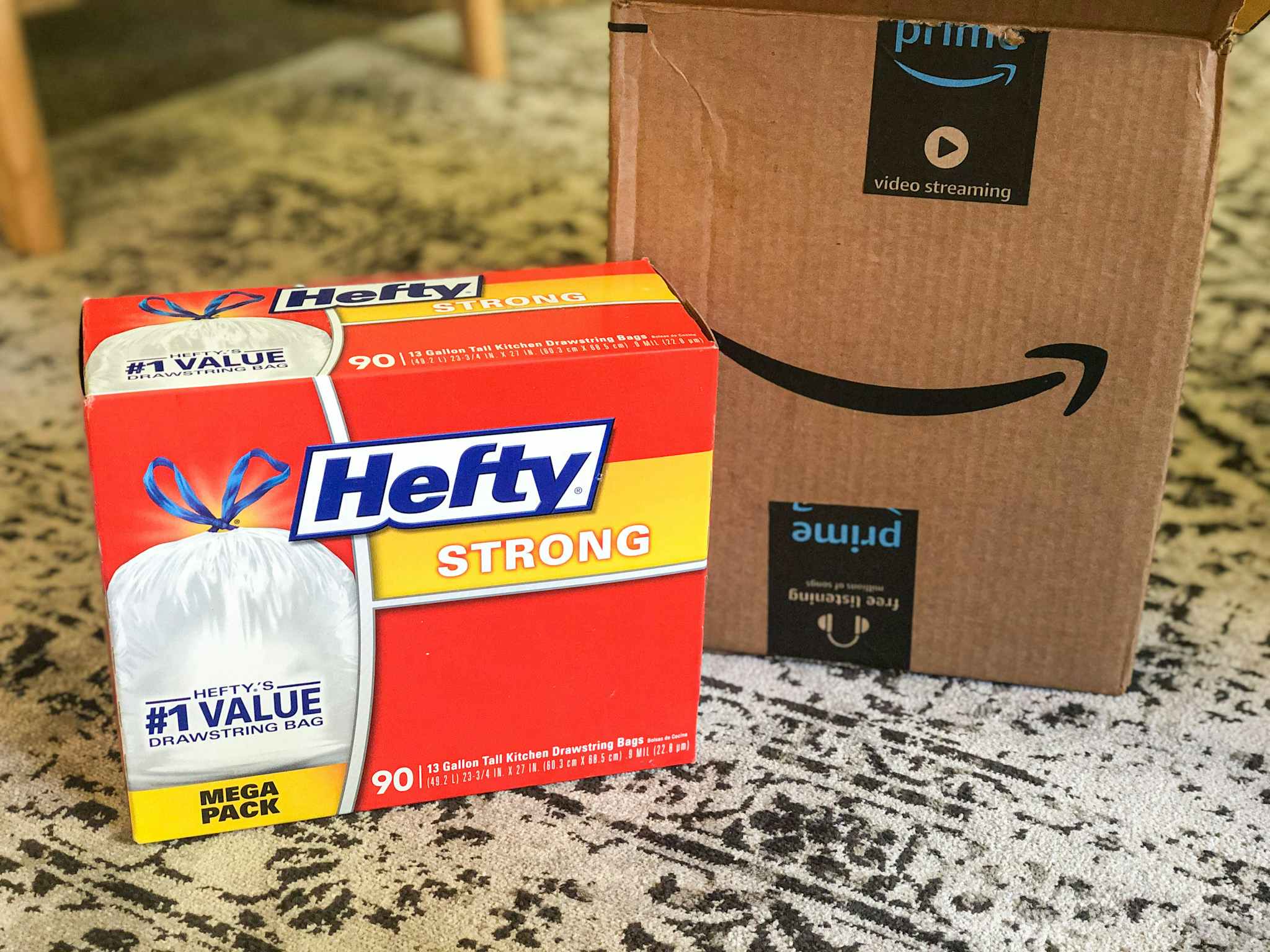 A box of Hefty trash bags next to an Amazon delivery box.