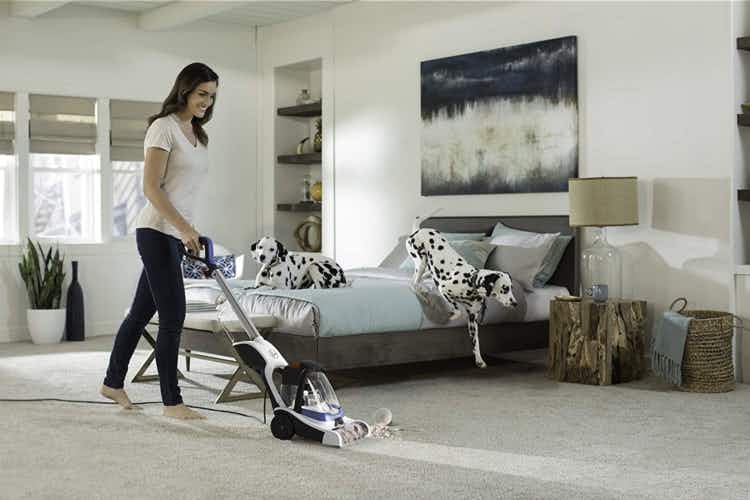 A woman vacuuming her carpet in her bedroom