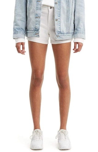 A woman wearing Levi's mid-length shorts with a white shirt and denim jacket