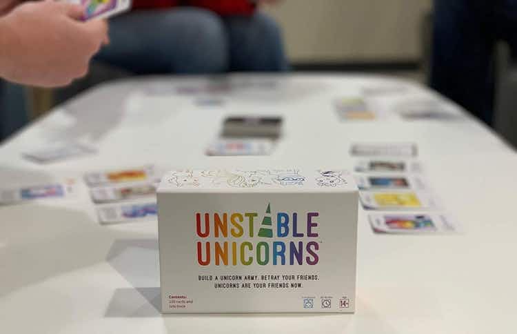 A few people playing the Unstable Unicorn card game on a table
