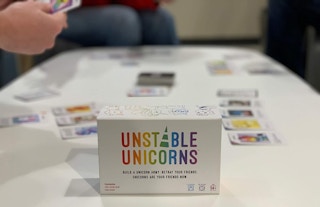 A few people playing the Unstable Unicorn card game on a table