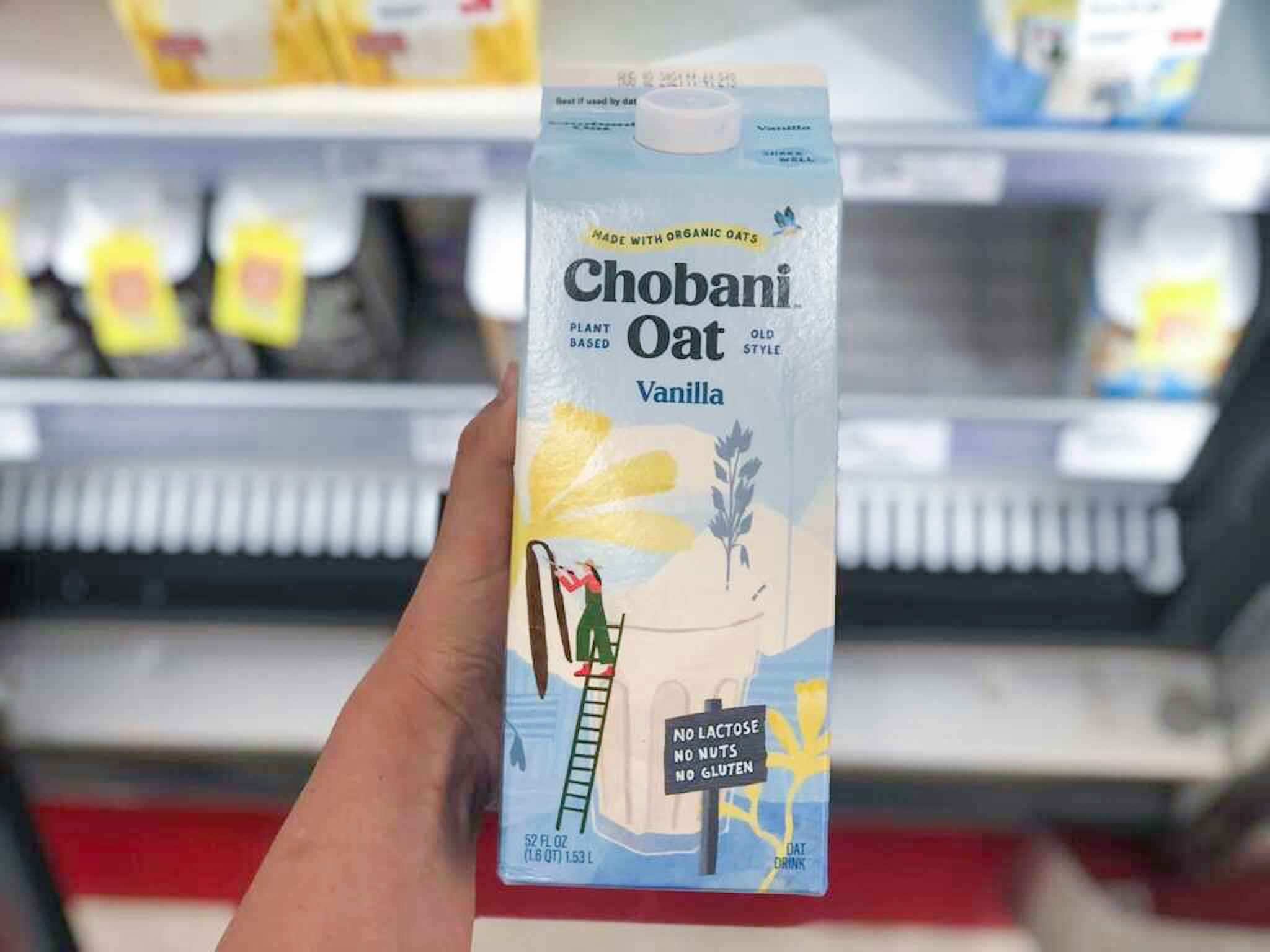 hand holding a carton of chobani oatmilk at target
