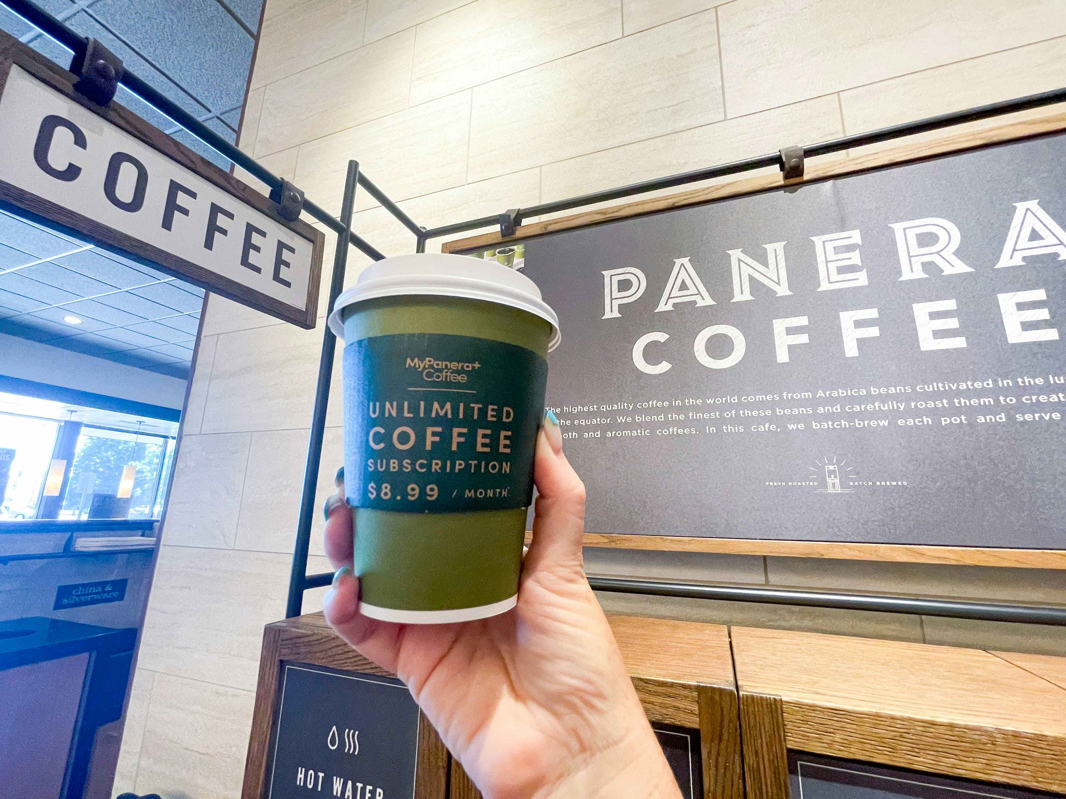 panera coffee being held in front of sign in store 