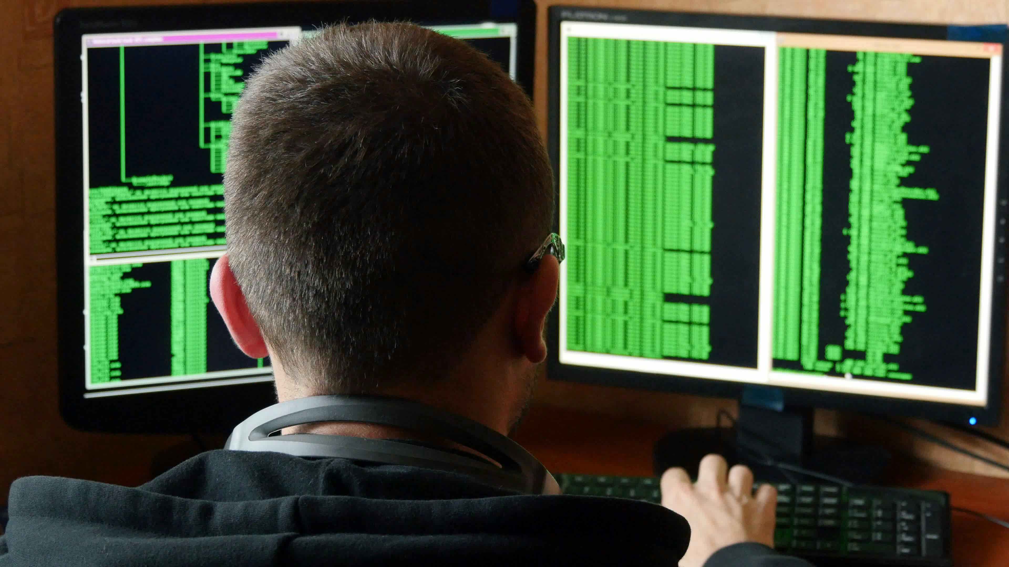 back of man's head in front of a computer with code