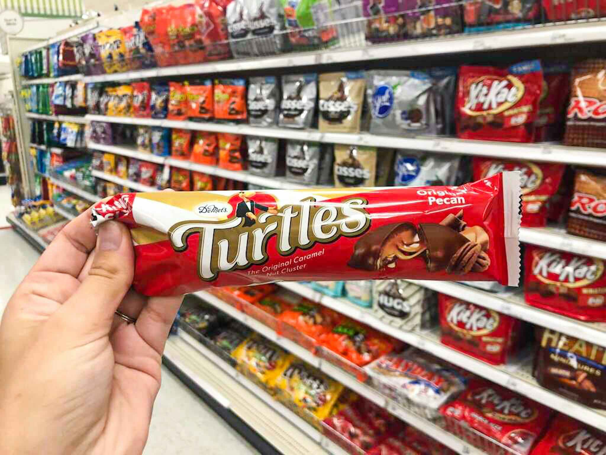 hand holding demet's turtles in the candy aisle at target