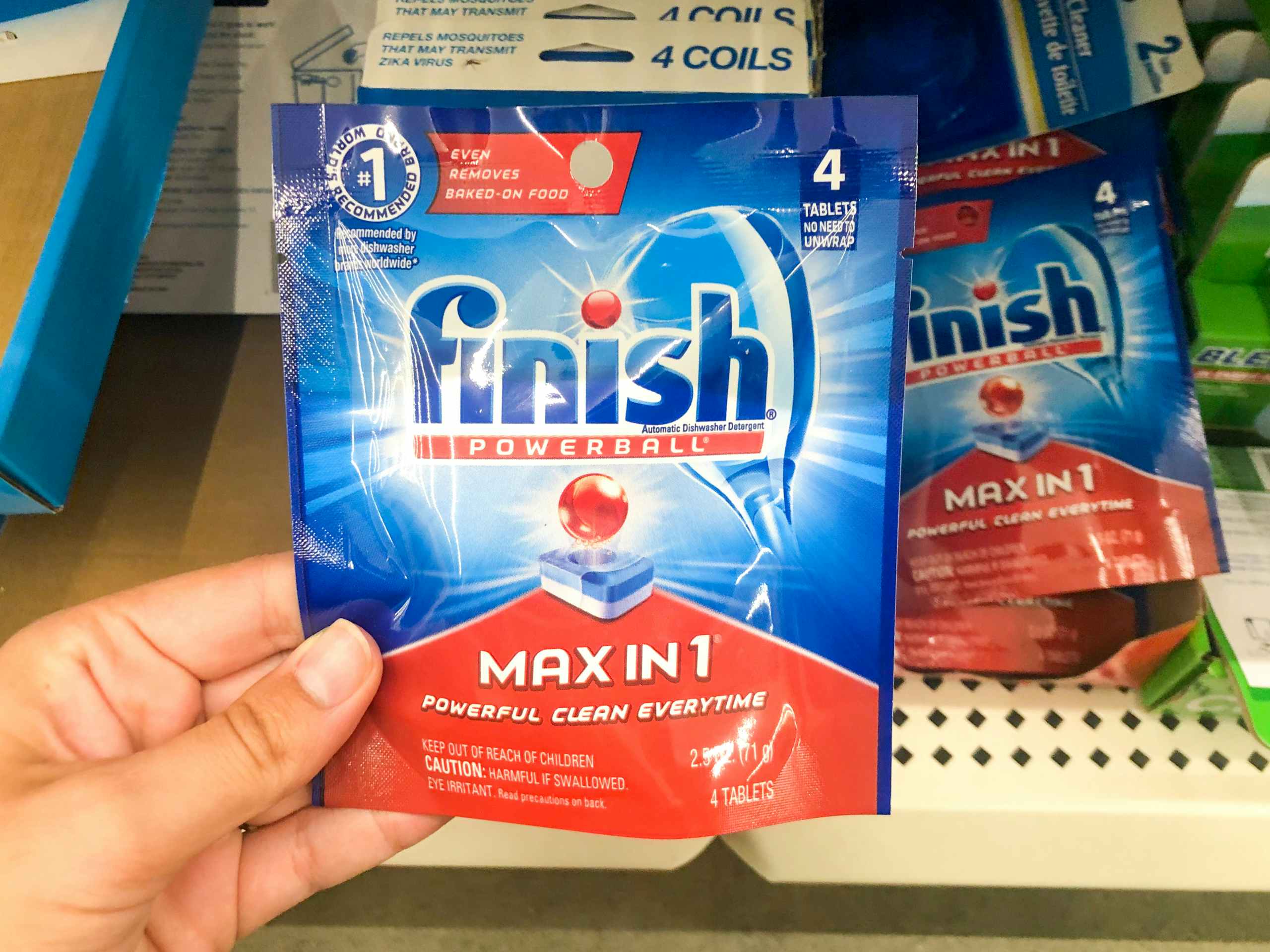 hand holding small pack of Finish dish detergent