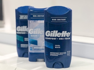 three bottles of deodorant standing upright on a clear, empty shelf