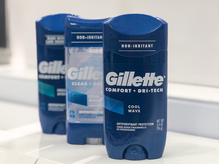 three bottles of deodorant standing upright on a clear, empty shelf