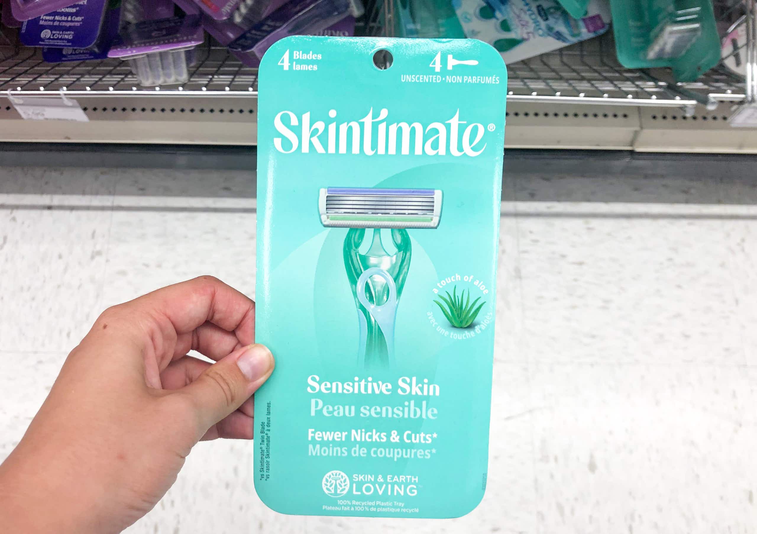 hand holding pack of disposable razors in front of store shelf