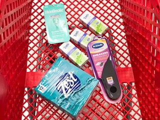 box of bar soap, shoe inserts, three boxes of toothpaste and a pack of razors in a shopping cart
