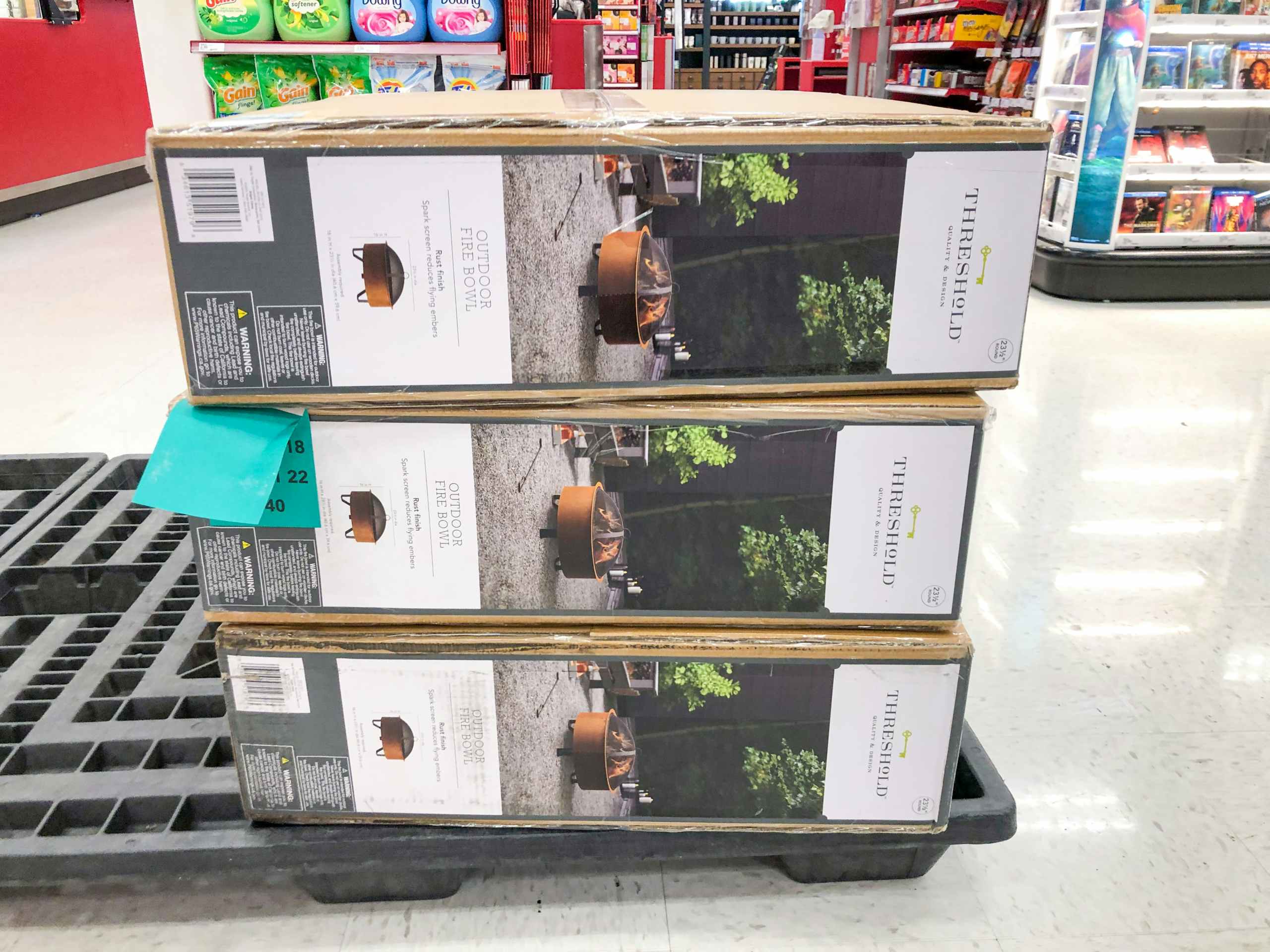 three boxes of fire pits stacked on a pallet inside Target