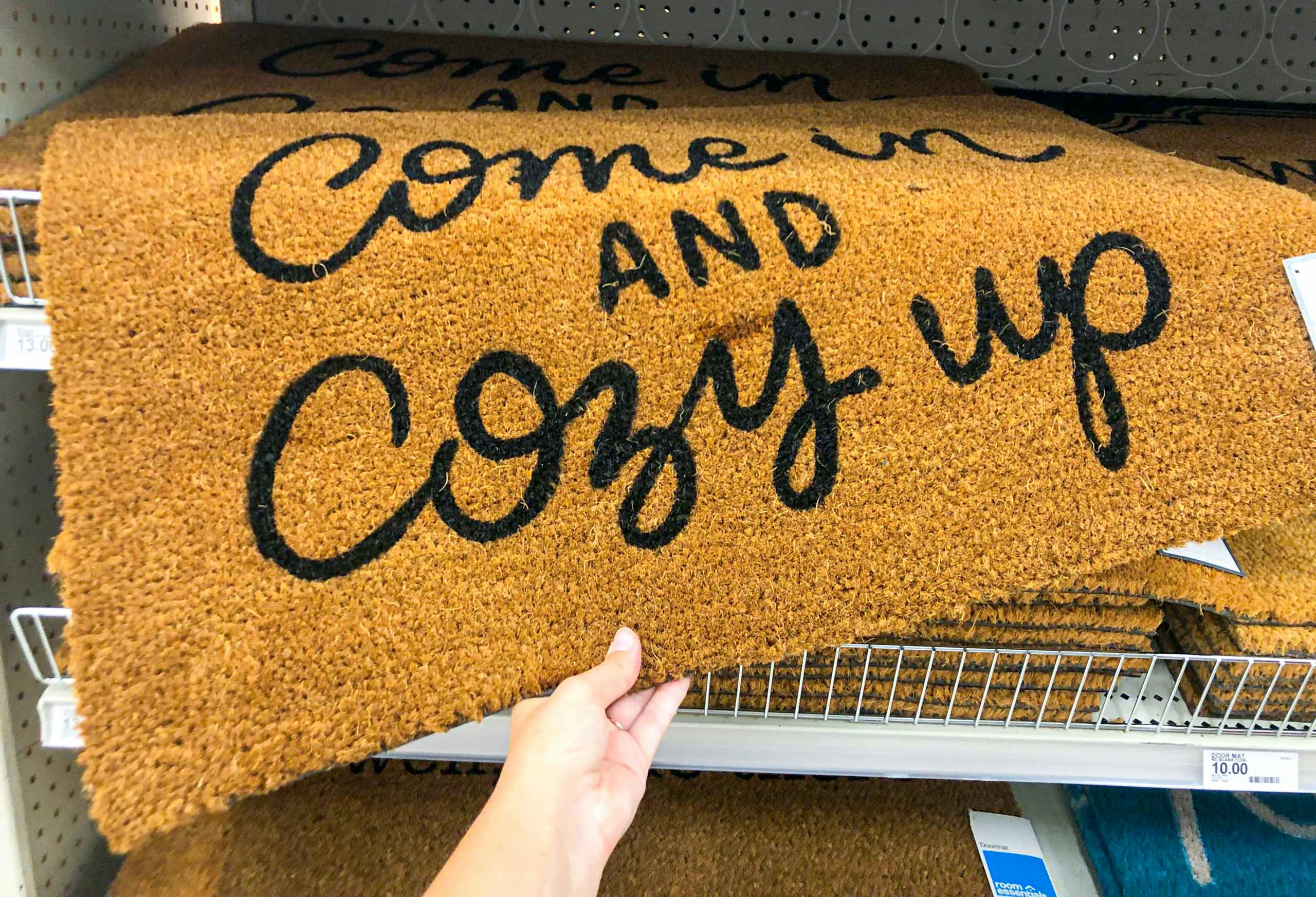 hand pulling doormat off the shelf at Target