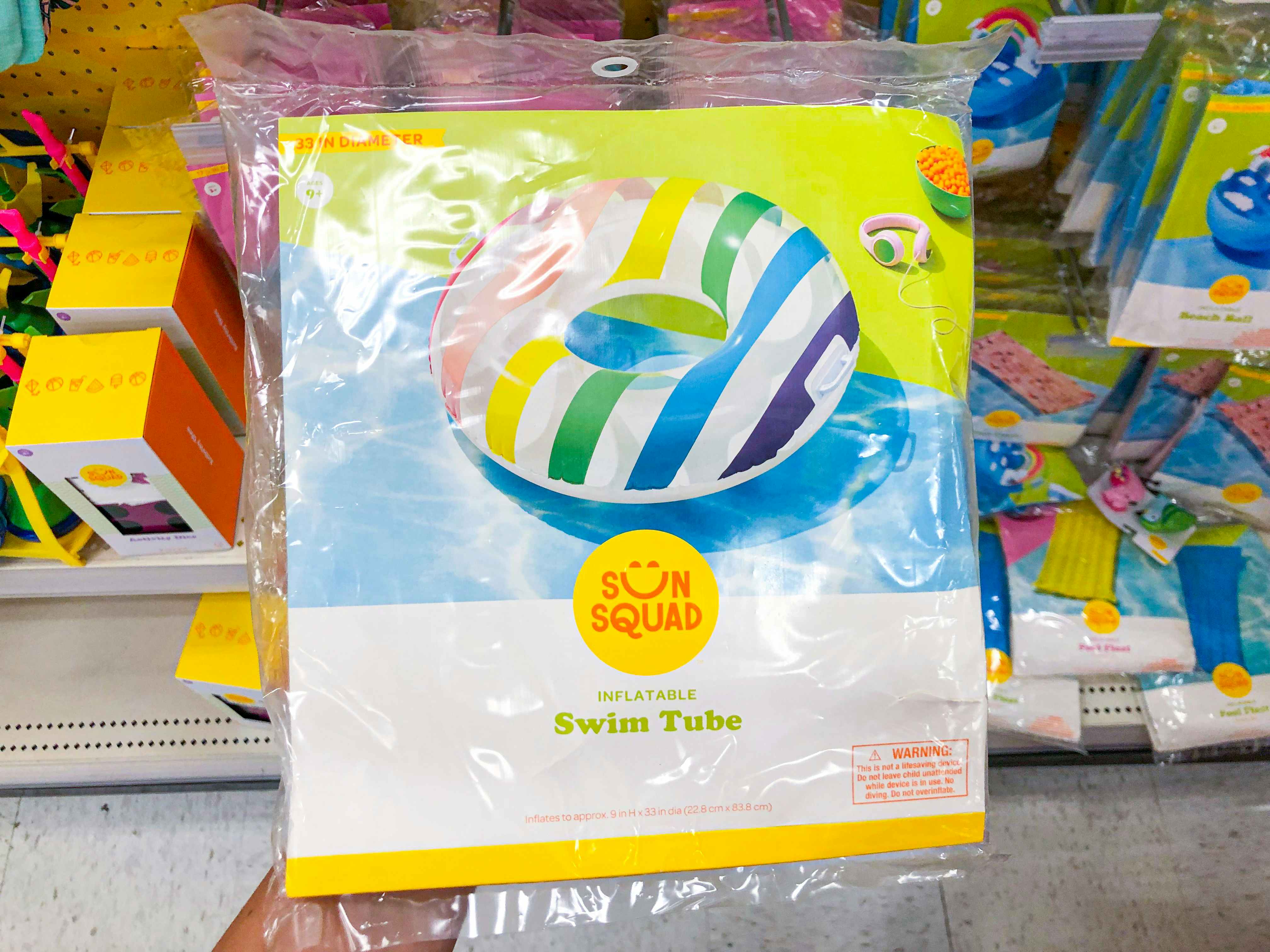 A person's hand holding a packaged Sun Squad inflatable pool float in the seasonal section at Target.
