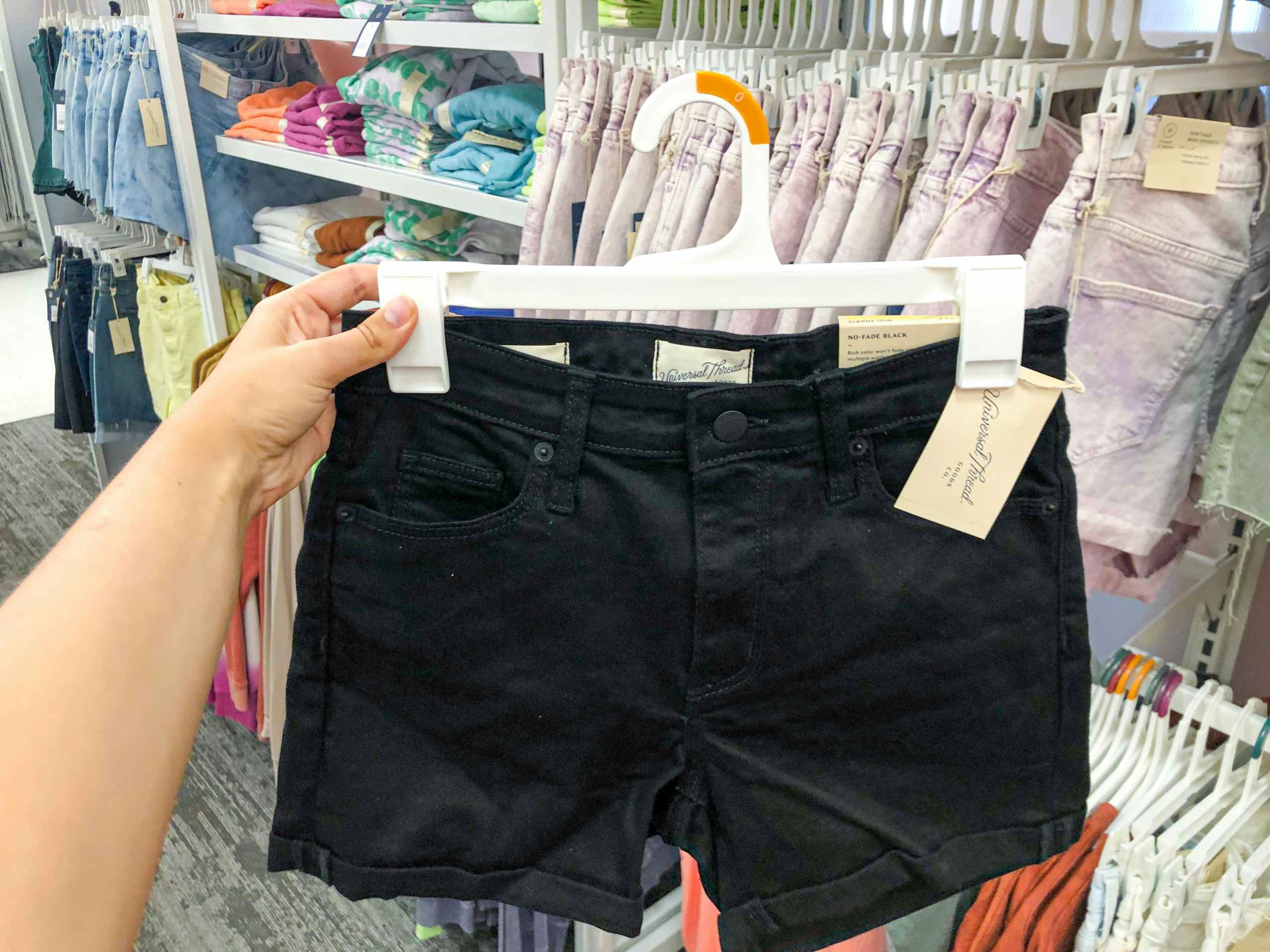 hand holding pair of shorts on hanger