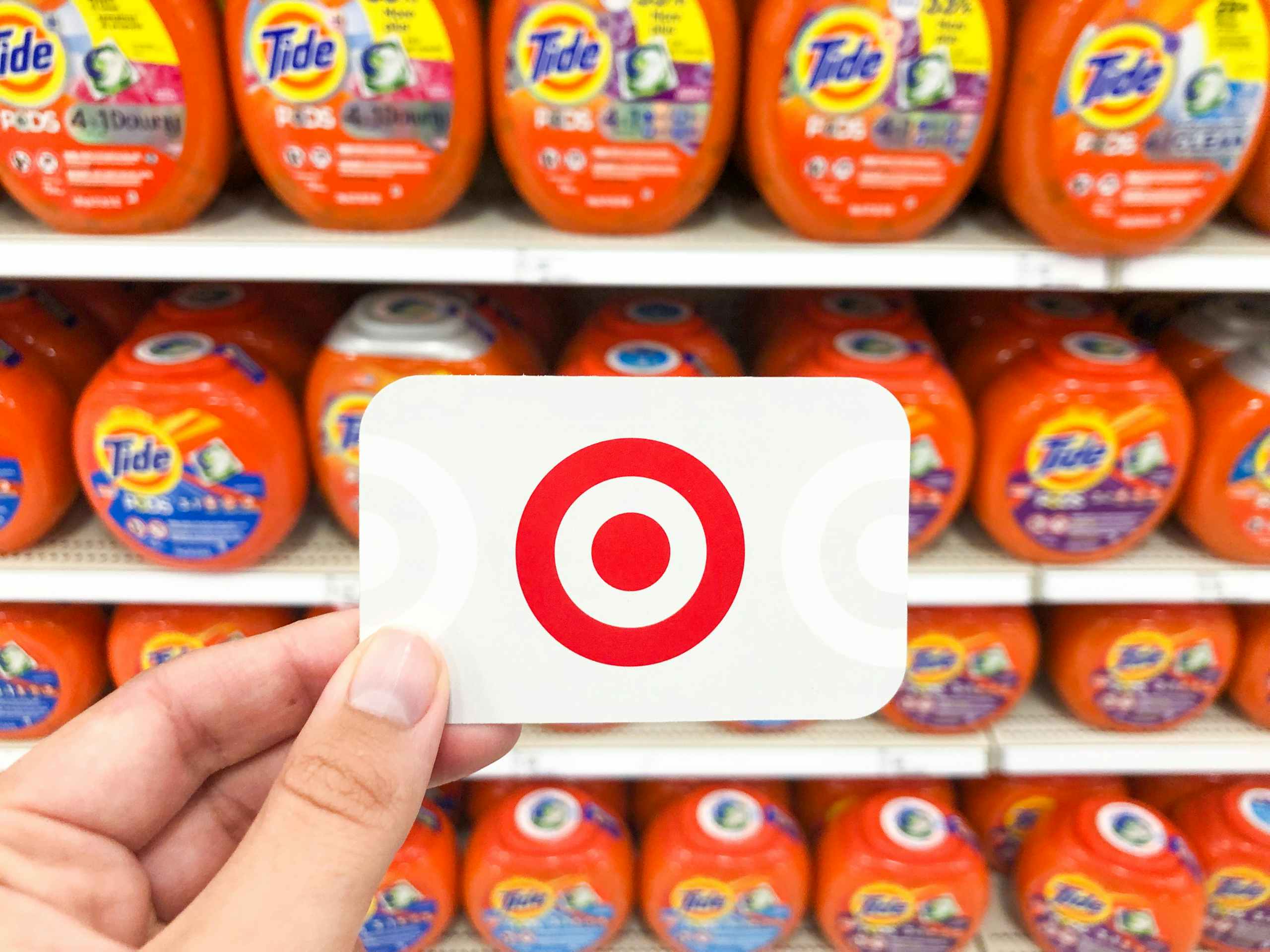 hnad holding target gift crad in front of Tide pods shelf