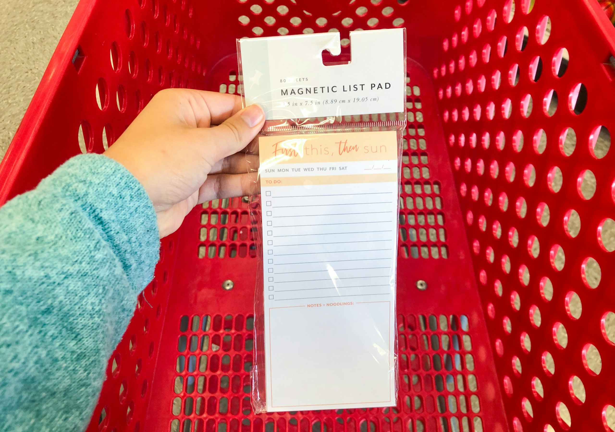 hand holding to do list pad over the top of a shopping cart