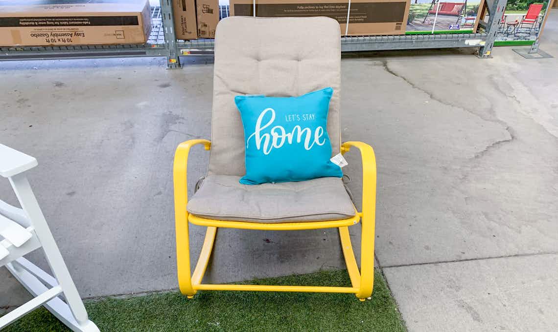 yellow metal rocking chair with tan cushion sitting in walmart garden center
