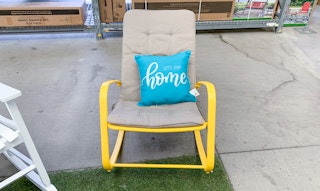 yellow metal rocking chair with tan cushion sitting in walmart garden center