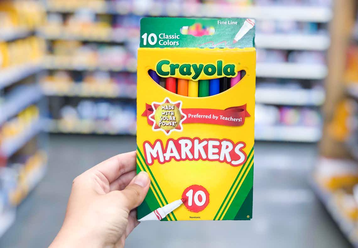 box of crayola classic colors thin markers held in front of markers on shelves