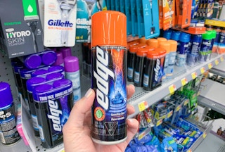 left hand holding a can of edge shaving cream in front of other shaving creams