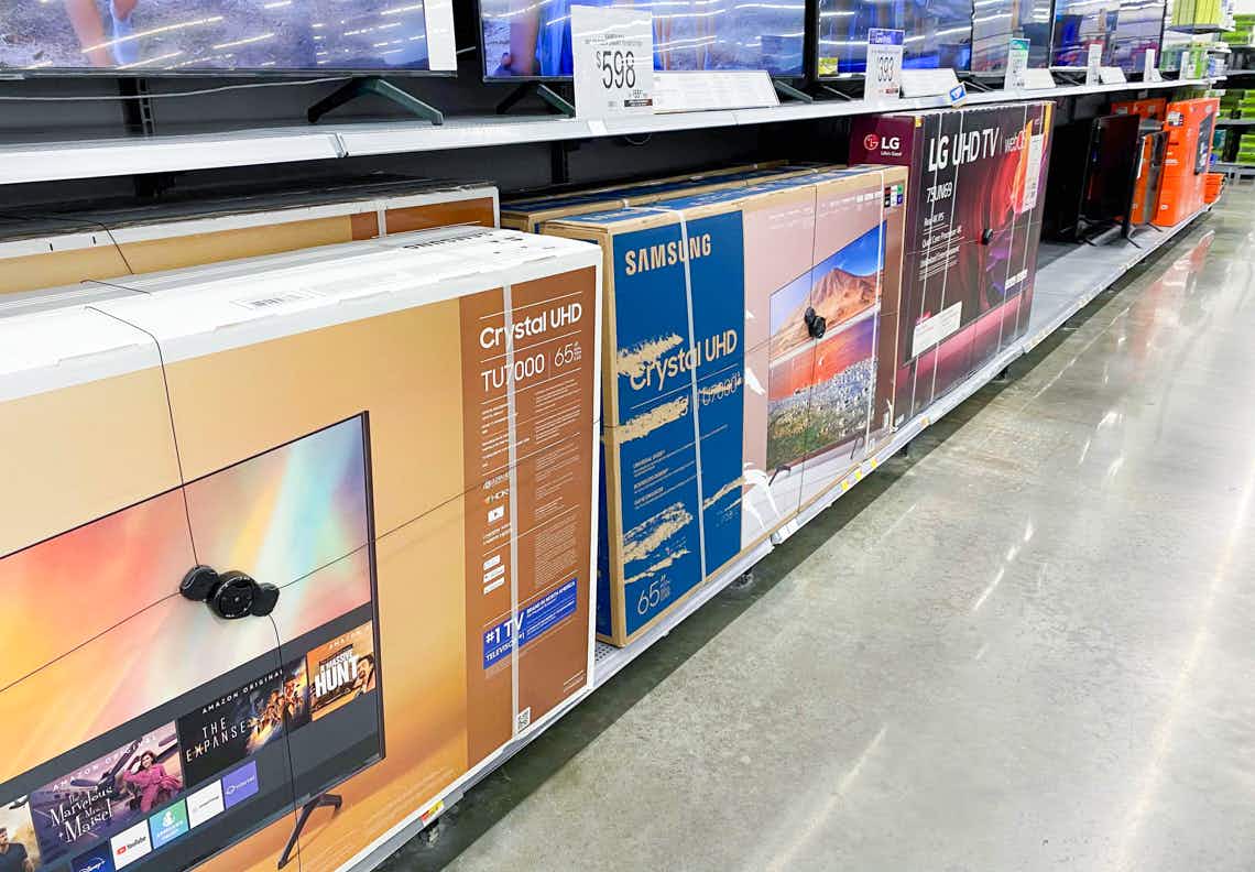 large screen tvs in boxes against back wall of walmart store