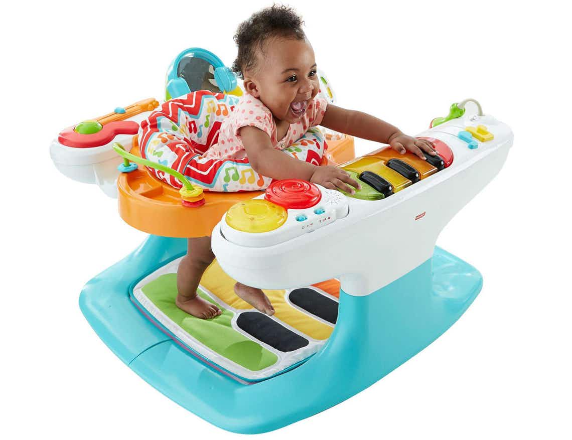 stock photo of fisher price piano baby bouncer on white background with baby girl playing 