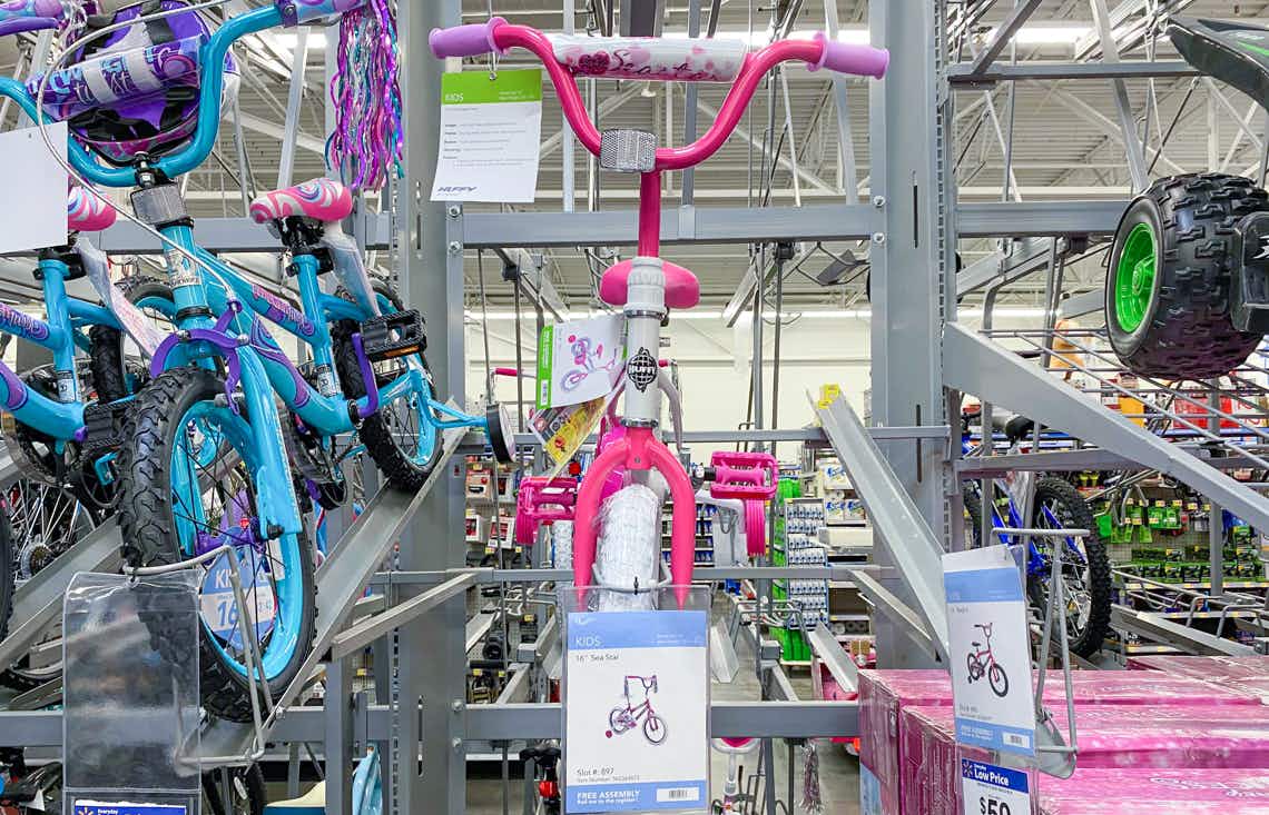 huffy girls 12 inch sea star bike with hot pink training wheels displayed on bike rack with other kids bikes on either side