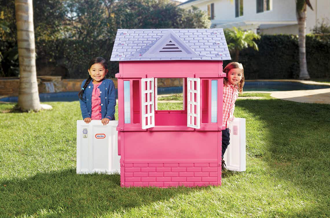 stock photo of little tikes cape cottage with two little girls playing in it ourdoors