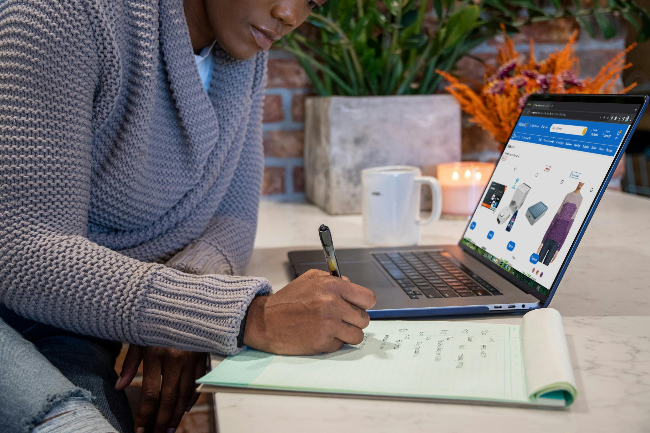 someone writing a list looking at the deals on Walmart's website