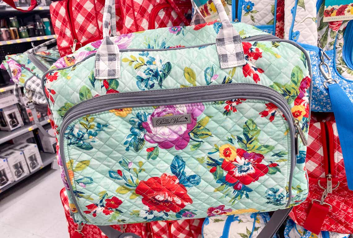 the pioneer woman quilted travel tote held up in front of more totes