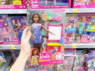 barbie art teacher set held in front of barbie shelves