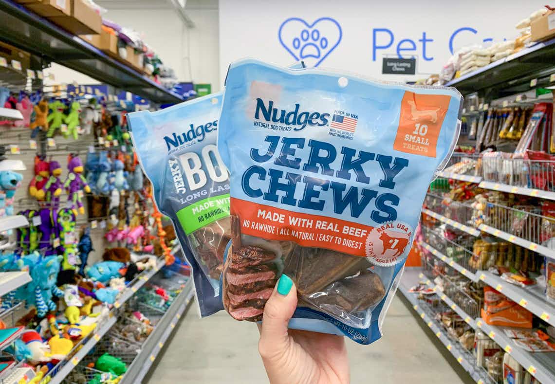 two bags of tyson nudges jerky treats for dogs being held in center of pet care aisle