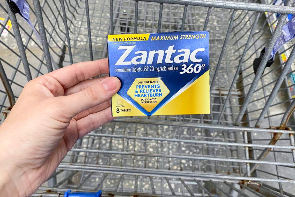 hand holding zantac 360 tablets above walmart cart
