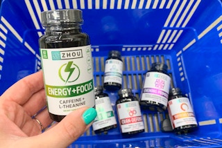 zhou nutitrion health supplements in a blue walmart basket with floor as background with a bottle of energy and focus being held up