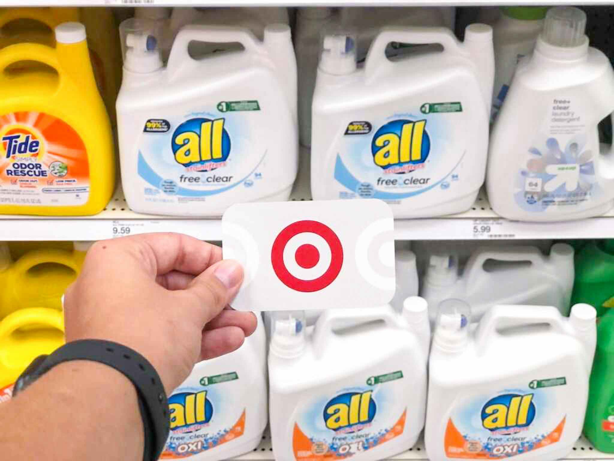hand holding a target gift card in front of all laundry detergent at target