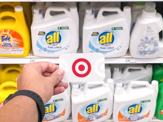 hand holding a target gift card in front of all laundry detergent at target