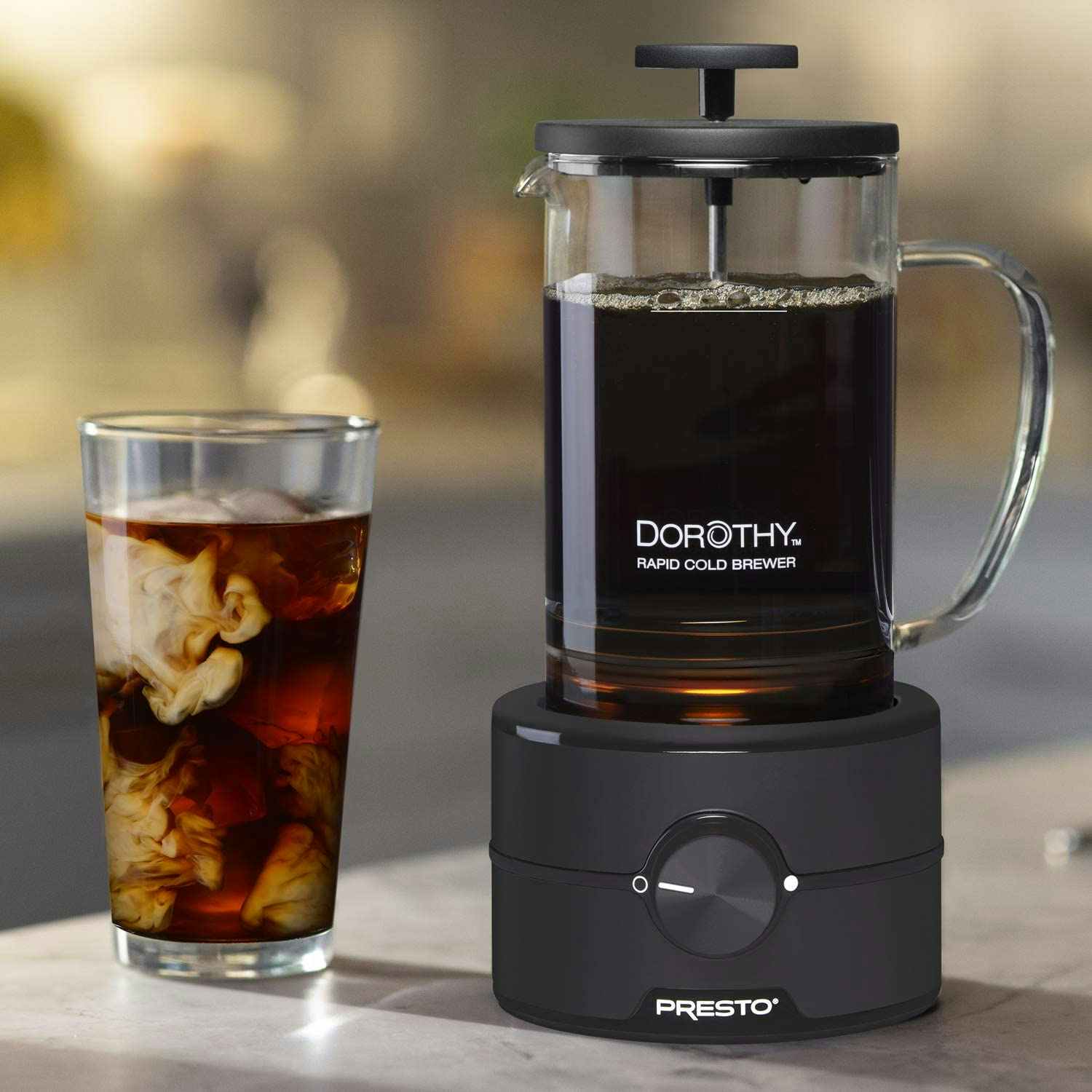 A Presto coffee cold brewer next to a cup of coffee.