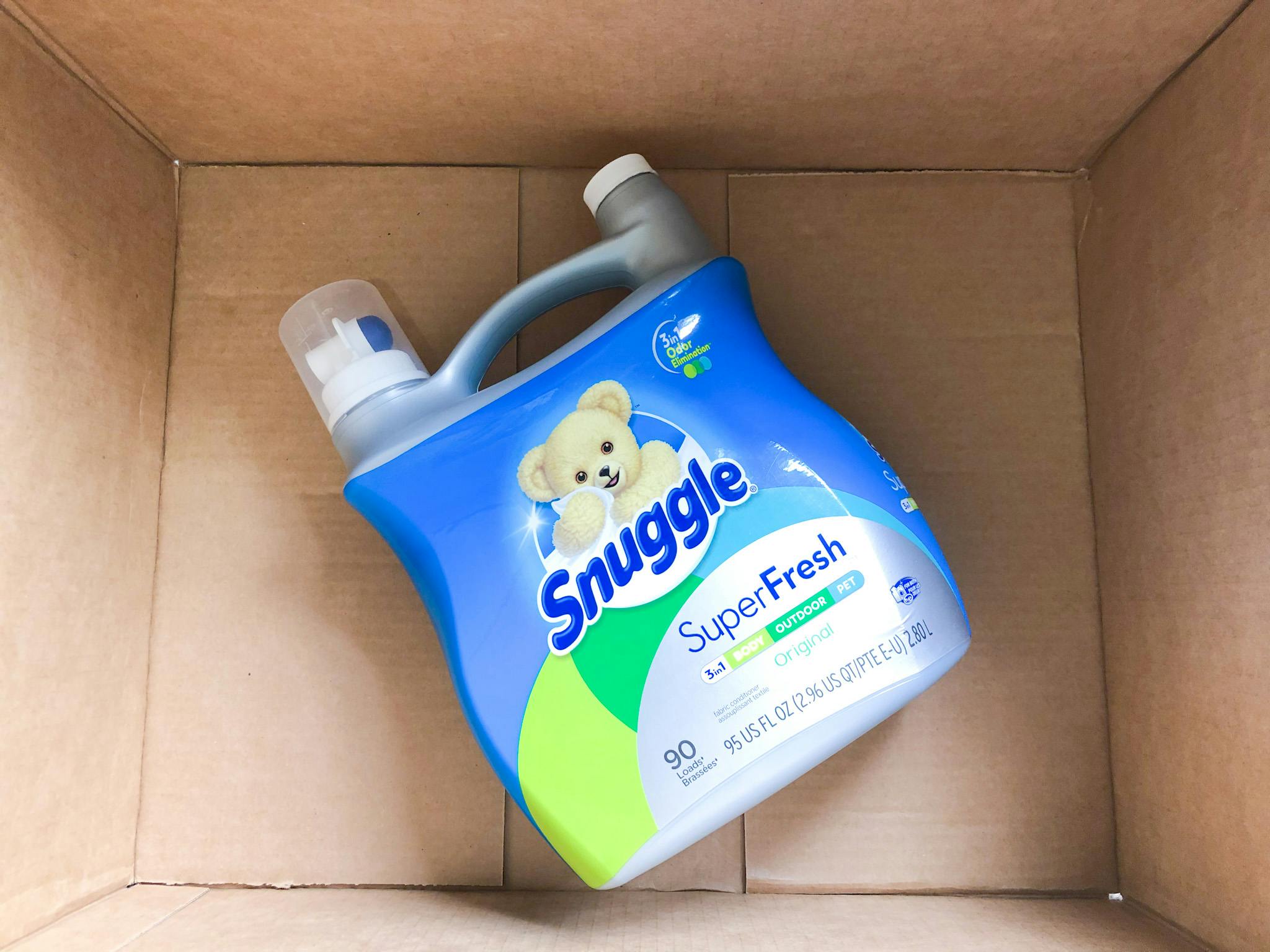 A bottle of Snuggle SuperFresh detergent sitting in a cardboard box.